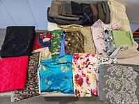 Overview of various folded fabric pieces in different colors and patterns including Asian, floral, Christmas, cotton, and velour materials.