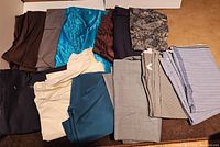 Top view of fabric pieces in various colors and patterns arranged on floor including solid browns, blues, cream, black, and striped fabrics.