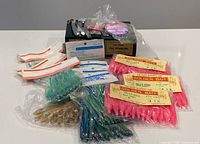 Multiple packs of different commercial fishing bait including pink, green, and blue soft plastic baits and fishing spoons with hooks.