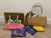 Overview photo showing all items arranged on the floor including the wicker handbag, fabric bags, felted wool pouch, beaded evening bag, yellow wallet, and card holder.