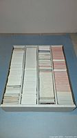 Top-down photo of large white box filled with four columns of tightly packed hockey cards, sorted into stacks with white backs visible on some and pink backs on others.