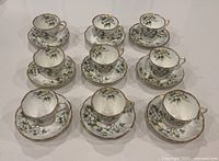 Nine Royal Albert White Dogwood teacups and saucers arranged in rows.