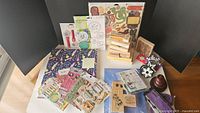 Photo of scrapbooking paper, chipboard stickers, and wooden stamps arranged upright and lying flat showing their designs.