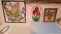 Lot contents showing metal hummingbird, oval stained glass tulips, and wood framed glass art