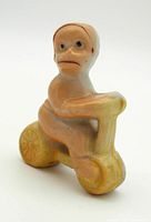 Front and side angle of ceramic monkey on yellow scooter figurine showing details in paint and form.