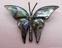 Front view of butterfly brooch showing abalone shell wing inlay and oxidized silver body and antennae.
