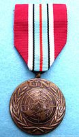 Front view of bronze UNDOF medal with United Nations emblem and striped ribbon.