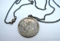 Front side of 1974 Kennedy Half Dollar coin pendant on chain showing John F. Kennedy's profile and the year 1974.