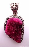 Front view of pink druzy quartz pendant with sterling silver decorative bail and chain-link border frame