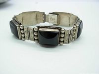 Close-up photo of bracelet showing square obsidian cabochons with silver bead and engraved silver links.