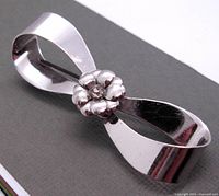Front view of the sterling silver bow-shaped brooch with boutonniere flower center detail showing polished surface and design.