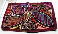 Front side of the textile artwork showing the colorful bird applique with geometric patterns on burgundy fabric.