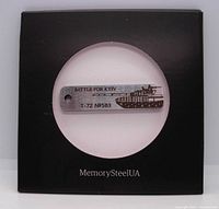 Metal key tag engraved with 'BATTLE FOR KYIV' and T-72 tank image, displayed in black packaging with circular window.