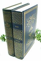 Two vintage hardcover books standing upright showing the black and gold embossed spines and front cover.