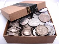 Box containing various Eastern Caribbean States coins in multiple denominations tightly packed in rolls and loose.