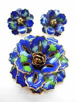 Front view of blue and green floral enamel brooch with matching earrings showing vibrant colors and gold-tone metal accents.
