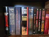 Front view of 12 Stephen King books showcasing titles and spine conditions, mainly hardcover editions with dust jackets.