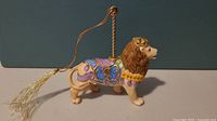 Side view of Lenox porcelain carousel lion showing colorful saddle, gold accents, and tassel