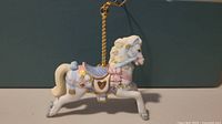 Side view of Lenox porcelain carousel horse ornament showing detailed decoration and gold hanging string.