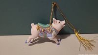 Side view of Lenox porcelain pig ornament showing detailed painted saddle and gold hanging tassel.