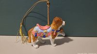 Side view of Lenox porcelain St Bernard carousel ornament showing detailed saddle and hanging string with tassel.
