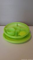 Green plastic sectioned tray with lid stacked, showing compartments and dip container on top