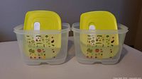 Two Tupperware FridgeSmart containers with yellow lids side by side showing front graphic and vented lids