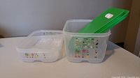 Two Tupperware FridgeSmart plastic containers side by side, one shallow and one deep, with their lids nearby on a white surface.