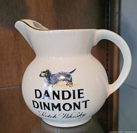 Front view of vintage Dandie Dinmont Scotch Whisky water jug showing dog illustration and branded text.