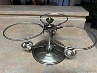 Photo showing the three-ring stainless steel stand with a copper base, designed to hold three bowls for serving.