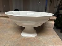 Photo of a large white ceramic plater with octagonal edges and a pedestal base, shown on a kitchen countertop.