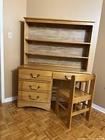 Front view of the desk with hutch and chair showing natural wood finish and drawer handles.