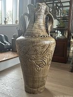 Full view of large ceramic vase with three handles and floral relief around the body