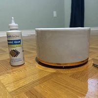 Side view of round white lazy Susan organizer next to a bottle of fabric glue for scale.