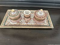 Front view of marble decorative set featuring one rectangular tray and three containers with jeweled tops and detailed beadwork