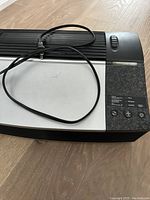 Full top view of the black and gray Oreck XL air cleaner unit with power cord coiled on top, showing control buttons on the right.