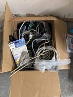 Top view of a cardboard box filled with assorted electronic wires and cables of different colors and sizes.