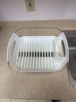 Top-down view of the white plastic dish rack showing the slotted base and built-in utensil holder.