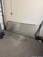 Metal dock ramp leaning horizontally against wall, front view