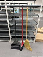 Front-side view showing two dust pans and three brooms with different types of handles and bristles