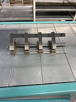 Front view of the metal four hole punch showing four punching heads aligned on a measurement scale.