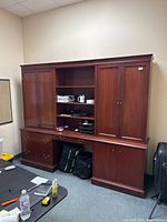 Front view of the large vintage wooden credenza showing open shelves in the middle and closed cabinets on the sides with items stored inside.