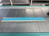 Blue plastic numbered card holder strip laying flat on a metal surface