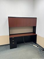 Front view of the office credenza showing upper laminated wood panel doors, fabric memo board middle, lower desktop, and drawer unit.