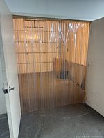 Clear PVC strip dock curtain hanging from a metal rail above a doorway, viewed from the inside.