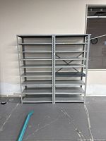 Front view of two adjacent metal shelving units against a wall, showing all shelves and structure.