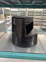 Side view of the round black plastic step stool showing textured grip surface and hollow carry section.