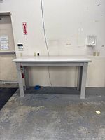Front view of the grey work table against a wall showing table height and width.