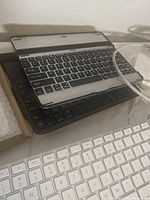 Stack of keyboards including black iPad keyboard, Apple Magic Keyboard, and black iPad keyboard case keyboard with USB charging cable.