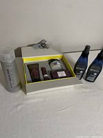Photo showing the Beekman lotion gift set with skincare items inside a decorative box, two Redken Extreme hair treatment bottles, and one Designline Mend the Ends conditioner bottle outside the box.